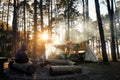 Camping tent tourism under pine forest trees landscape backlit by golden sunlight with sun rays pouring through trees. Campground Royalty Free Stock Photo