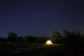 Camping tent under beautiful night sky full of stars. Starry night sky above illuminated touristic tent
