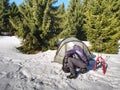 Camping in tent in winter forest. Snowshoes trek in mountains