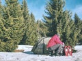 Camping in tent in winter forest. Snowshoes trek in mountains