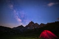 Camping under starry sky and milky way at high altitude on the Alps. Illuminated tent in the foreground and majestic mountain peak Royalty Free Stock Photo