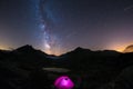 Camping under starry sky and milky way at high altitude on the Alps. Illuminated tent in the foreground and majestic mountain peak Royalty Free Stock Photo