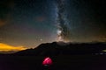 Camping under starry sky and milky way at high altitude on the Alps. Illuminated tent in the foreground. Mars Planet on the left. Royalty Free Stock Photo