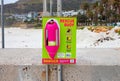 Colorful pink rescue buoy attached to a light green sign.