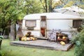 Halloween design home. Interior cozy yard campsite with fall flowers potted and pumpkins. Wooden RV house