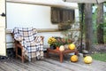 Interior yard campsite with flowers potted and pumpkins. Wooden armchair near outside caravan trailer decorated for Halloween