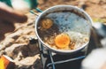 Campsite lifestyle, person cooking fried eggs in nature camping outdoor, prepare scrambled omelette, breakfast picnic on metal Royalty Free Stock Photo