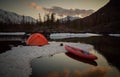 Campsite with orange tent and canoe on a lake