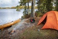 Campsite with orange tent on northern Minnesota lake during an autumn morning