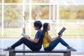 On a campus, a couple of students are studying together, and a teenager sits on a seat beside a sports court with a book Royalty Free Stock Photo