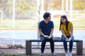 On a campus, a couple of students are studying together, and a teenager sits on a seat beside a sports court with a book Royalty Free Stock Photo