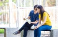 On a campus, a couple of students are studying together, and a teenager sits on a seat beside a sports court with a book Royalty Free Stock Photo