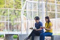 On a campus, a couple of students are studying together, and a teenager sits on a seat beside a sports court with a book Royalty Free Stock Photo