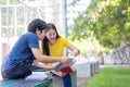 On a campus, a couple of students are studying together, and a teenager sits on a seat beside a sports court with a book Royalty Free Stock Photo