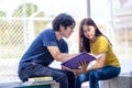 On a campus, a couple of students are studying together, and a teenager sits on a seat beside a sports court with a book Royalty Free Stock Photo