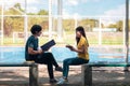 On a campus, a couple of students are studying together, and a teenager sits on a seat beside a sports court with a book Royalty Free Stock Photo