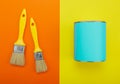 Can of blue paint and paintbrush on orange and yellow background Royalty Free Stock Photo