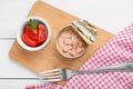 Can of conserved tuna and tomatoes on white wooden table, top view