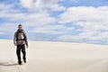 He can handle the desert heat. a young male hiker walking along the sand dunes. Royalty Free Stock Photo