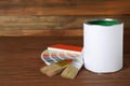 Can of paint, brushes and color palette samples on wooden table Royalty Free Stock Photo