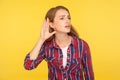 Can`t hear you! Portrait of attentive ginger girl in checkered shirt holding hand near ear trying to listen quiet conversation