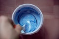 Can of white-blue paint mixing with a brush, top view. Royalty Free Stock Photo