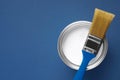 Can with white paint and brush on blue background, top view. Space for text Royalty Free Stock Photo