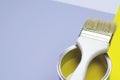 A can of yellow paint with a brush on a gray-yellow with a white background Royalty Free Stock Photo