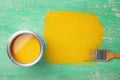 Can of yellow paint and brush on green wooden background, flat lay. Royalty Free Stock Photo