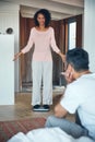 Can you see the difference. a mature woman weighing herself on a scale while her husband watches. Royalty Free Stock Photo