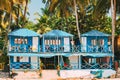 Canacona, Goa, India. Famous Painted Guest Houses On Beach Against Background Of Tall Palm Trees In Sunny Day