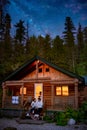 Canada British Colombia Cabin in the woods forest at night, couple drinking in front of wooden cabin, A remote cabin in Royalty Free Stock Photo