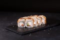 Canada eel sushi rolls with cucumber and salmon on a stone plate over black background Royalty Free Stock Photo