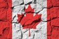 Canada flag depicted in paint colors on old stone wall closeup. Textured banner on rock wall background