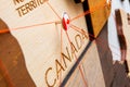 Canada flag on the pushpin and red threads on the wooden map