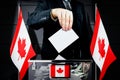 Canada flags, hand dropping voting card - election concept Royalty Free Stock Photo