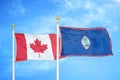 Canada and Guam two flags on flagpoles and blue cloudy sky