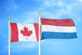 Canada and Netherlands two flags on flagpoles and blue cloudy sky