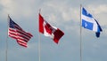 Canada, USA, and Quebec flags waving in the wind cloudy day Royalty Free Stock Photo