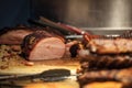 Canadian bacon, also known as peameal, for sale, grilled and cooked, being ready to be cut on a wooden plank