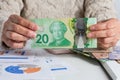 Canadian currency. Dollars. Retired woman holding bill on desk office