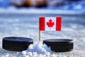 Kanadská vlajka na špáradlo medzi dvoma hokejovými pukmi. Kanada bude hrať na Svetovom pohári v skupine A. 2019 IIHF World