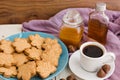 Canadian maple cream cookies on blue plate with honey, maple syrup, acorns and white cup of black coffee