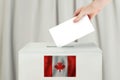 Canadian Vote concept. Voter hand holding ballot paper for election vote on polling station
