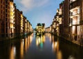 Canal amidst illuminated buildings in old warehouse district Speicherstadt in Hamburg at night Royalty Free Stock Photo