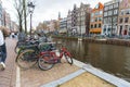 Canal in Amsterdam. Bikes of different sizes and colours standing by canal. Outdoor shot. Touristic destination.