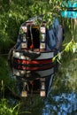 A canal boat moored in the Lee & Stort canal in Hertfordshire under a willow tree