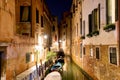 Canal with boats and a small bridge in Venice at night, Italy. Venice postcard. Royalty Free Stock Photo