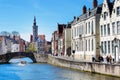 Canal and bridge view, boat with tourists, church tower in Brugge, Belguim