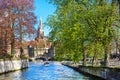 Canal and bridge view, boat with tourists, church tower in Brugge, Belguim